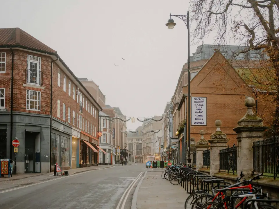 A quiet brick-lined street with small shops and parked bicycles on an overcast morning